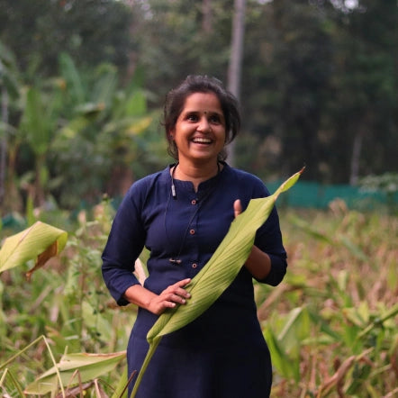 Geetha standing among fully grown turmeric plants in her farm
