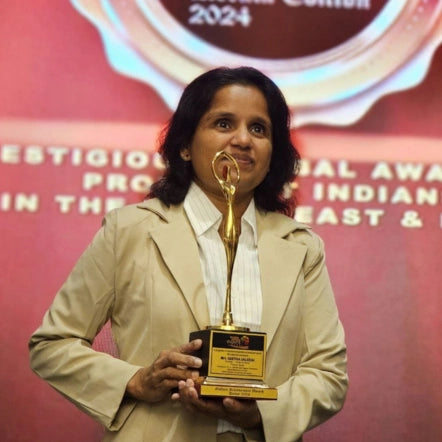 Geetha holding the Dubai Golden Achievements Award 2024 at an international event